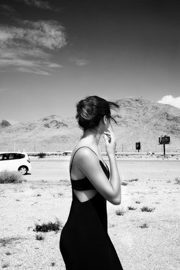 Aliona Kuznetsova: 'lost in the wind', 2020 Black and White Photograph, Romance. A woman facing away from the camera, yet we can understand she is overwhelmed. A gust of wind moved her hair and we can also see a fragment of a car behind her. ...