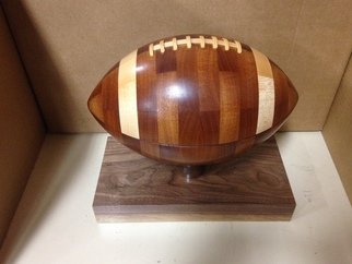 John Cummings: 'segmented wooden football', 2021 Woodworking Art, Sports. Carefully and accurately segmented from premium woods, this master piece can be used as a mantle piece display or a gift to that special athlete.  Made of 80 pieces of wood, typically walnut, maple, or sapele.  Wooden base or wooden  Tee  can be added for an additional fee. ...