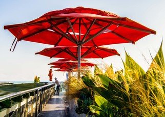 Dick Drechsler: 'the umbrellas of venice', 2018 Color Photograph, Urban. Towering over the Pacific Ocean this restaurant shelters its patrons from the sun with these colorful red umbrellas. ...