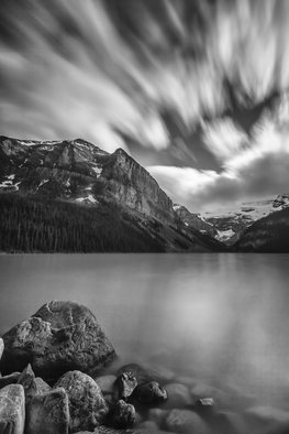 Jon Glaser, 'Falling Sky', 2013, original Photography Black and White, 16 x 24  x 1 inches. Artwork description: 3891 This Photograph was taken in Lake Louis, which is located in Banff National Park. The lake was calm while the clouds moved swiftly across the sky. This image was created using a longer exposure in the camera. The mountains have snow on them while the trees at ...