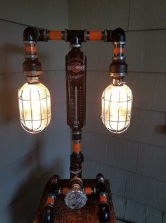 Laura Johnson: 'harley davidson pipe lamp', 2019 Other, Light. LETS RIDE This unique hand crafted lamp is made of 34 black pipe.  It is customized with a harley davidson gas cap for on off knob.  This unique lamp also had a Harley Davidson Thermometer.  UL Listed 5 foot cord with antique style plug.  Comes with 2- led light bulbs ...
